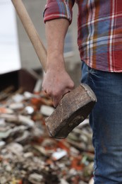 Man with sledgehammer on blurred background, closeup