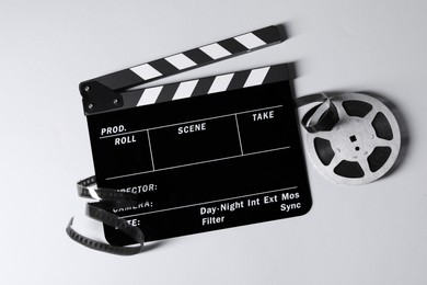 Clapperboard and film reel on grey background, flat lay