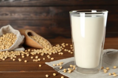 Photo of Fresh soy milk and beans on wooden table. Space for text