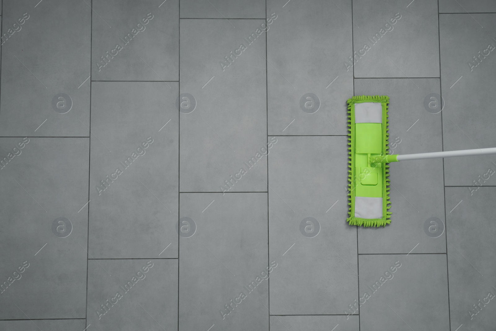 Photo of Cleaning grey tiled floor with microfiber mop, top view. Space for text