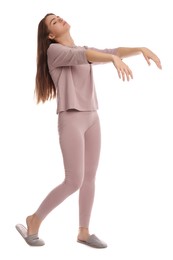 Photo of Young woman wearing pajamas and slippers in sleepwalking state on white background