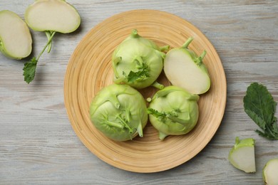 Photo of Whole and cut kohlrabi plants on wooden table, flat lay