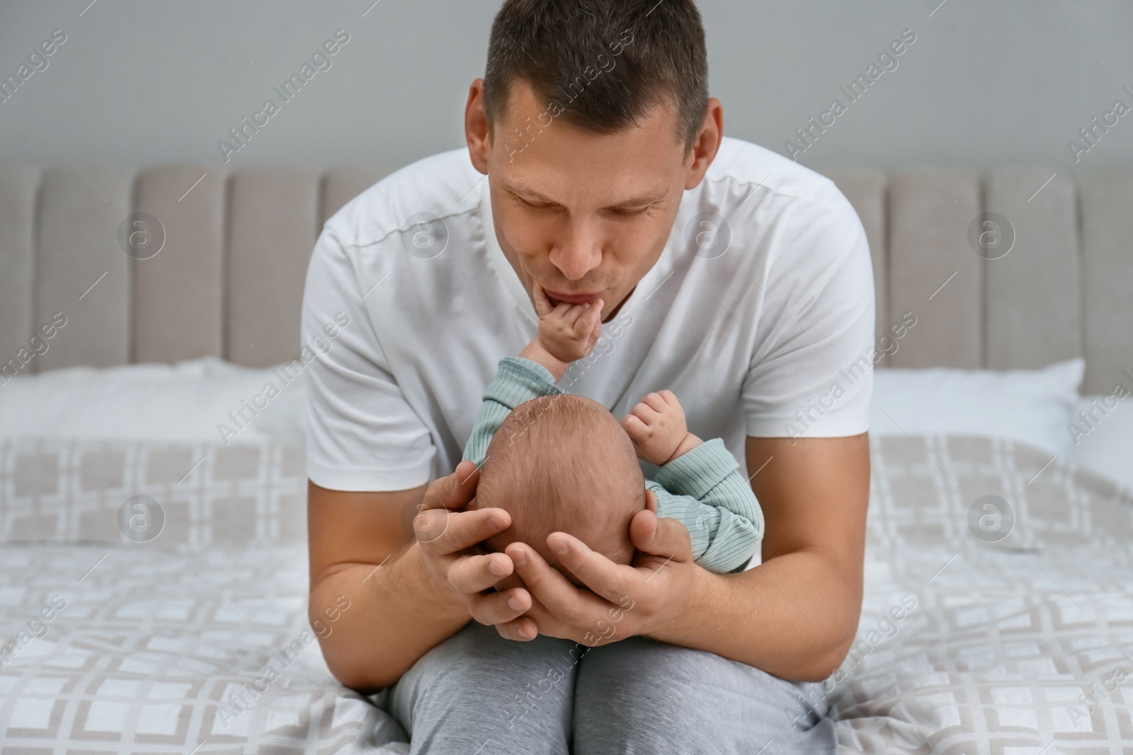 Photo of Happy father holding his cute baby on bed at home