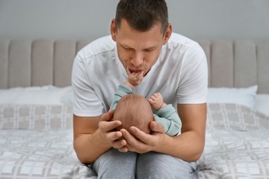 Happy father holding his cute baby on bed at home