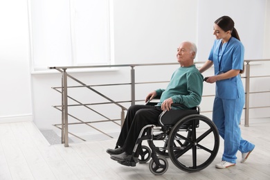 Photo of Nurse assisting senior man in wheelchair at hospital