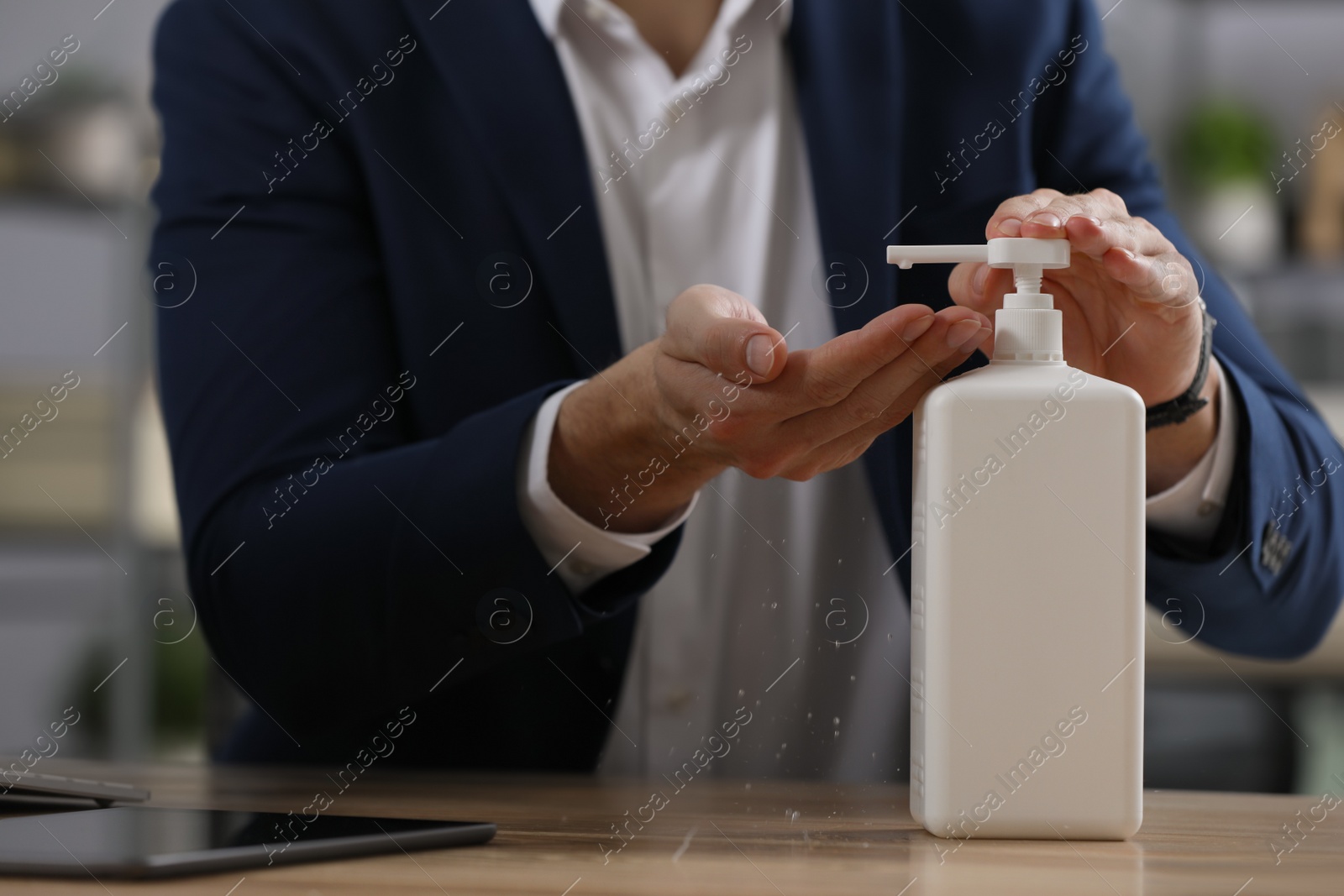 Photo of Man applying hand sanitizer in office, closeup. Personal hygiene during Coronavirus pandemic