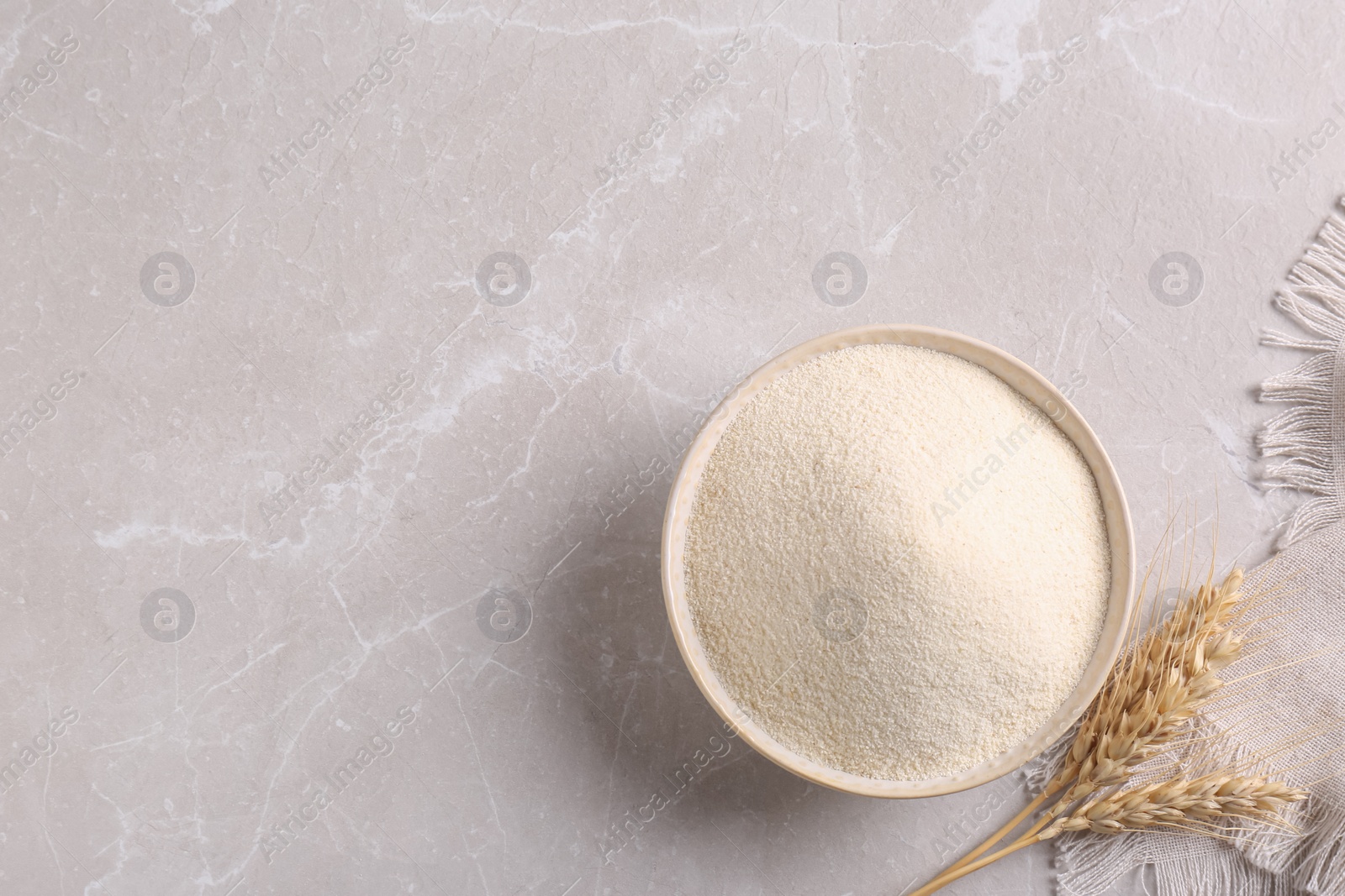 Photo of Uncooked organic semolina and spikelets on light table, flat lay. Space for text