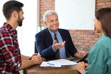 Senior notary working with young couple in office