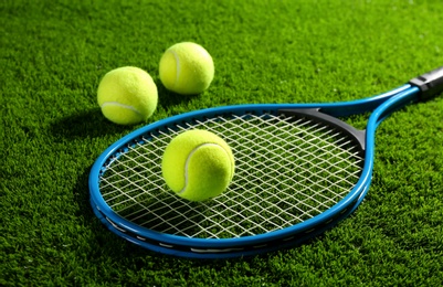 Photo of Tennis racket and balls on green grass. Sports equipment