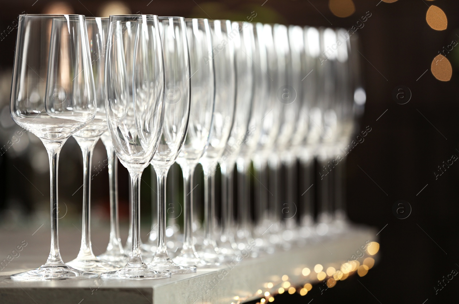 Photo of Set of empty glasses on grey table against blurred background