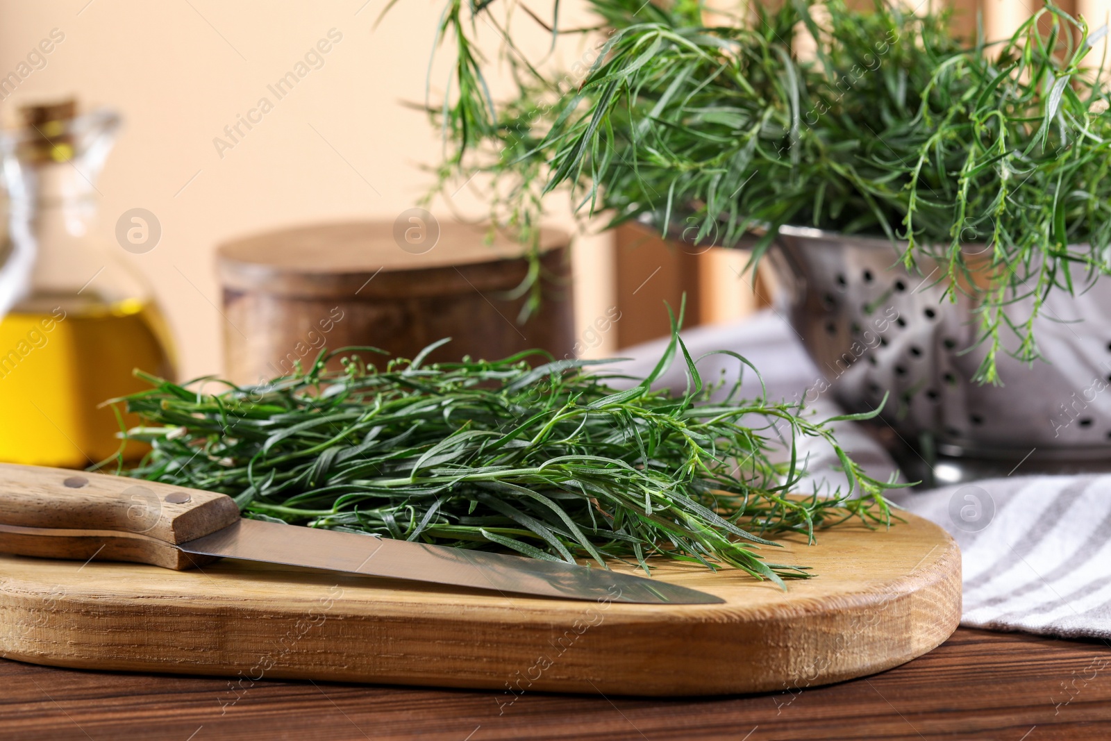 Photo of Board with fresh tarragon leaves and knife on wooden table