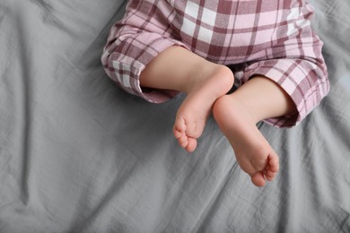 Photo of Little baby in pajamas on bed, top view. Space for text