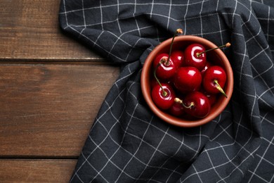Photo of Sweet red cherries in bowl on wooden table, top view. Space for text