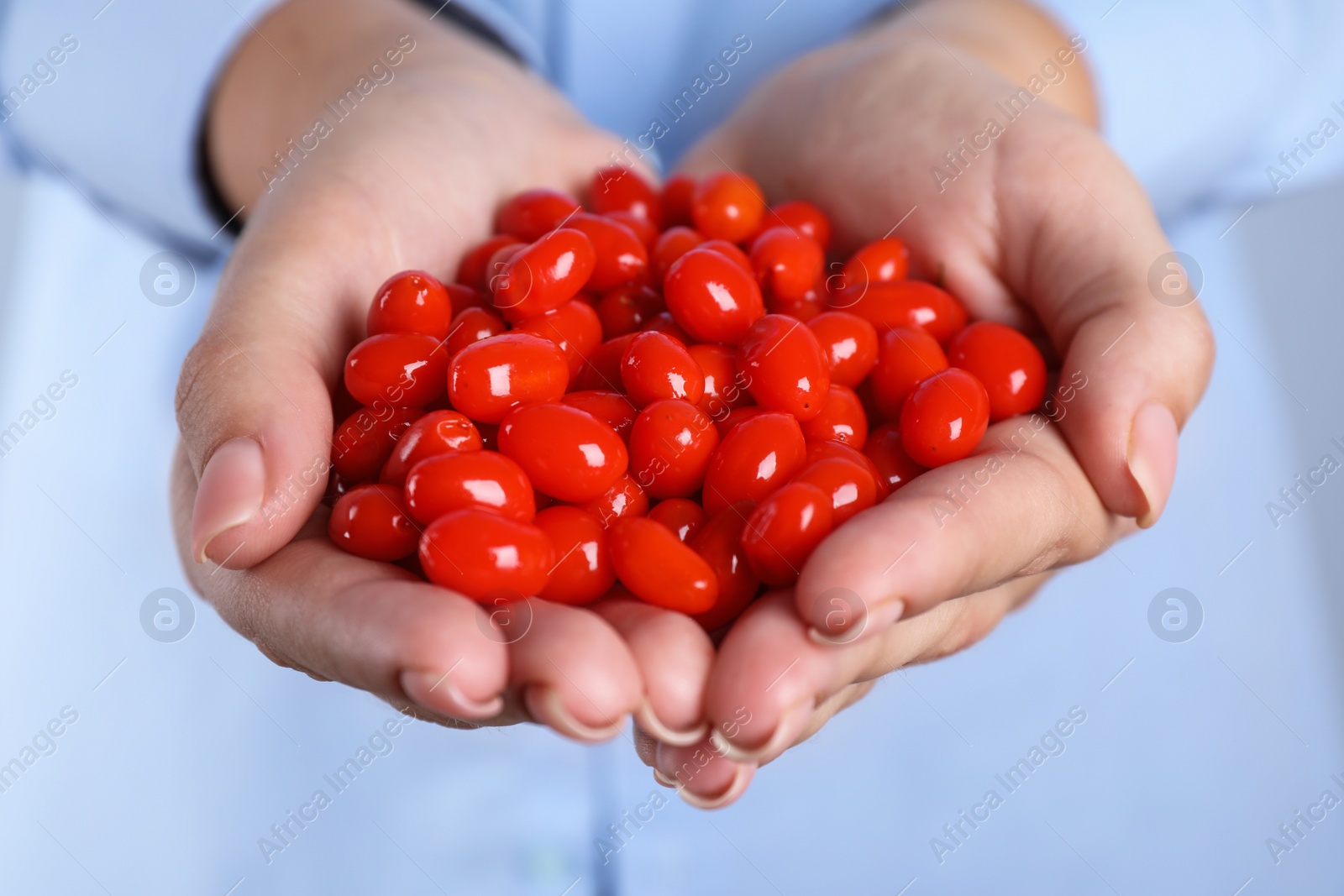 Photo of Woman holding fresh goji berries, closeup view