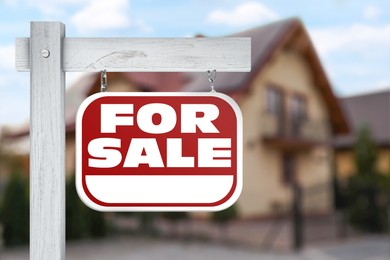 Image of Sale sign near beautiful house outdoors. Red signboard with words