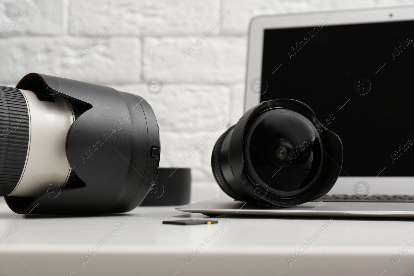 Photo of Laptop and professional photographer's equipment on table indoors