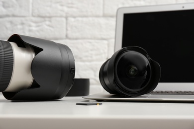 Laptop and professional photographer's equipment on table indoors