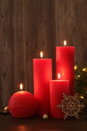 Photo of Beautiful burning candles with Christmas decor on wooden table
