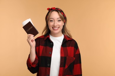 Happy young woman with passport and ticket on beige background