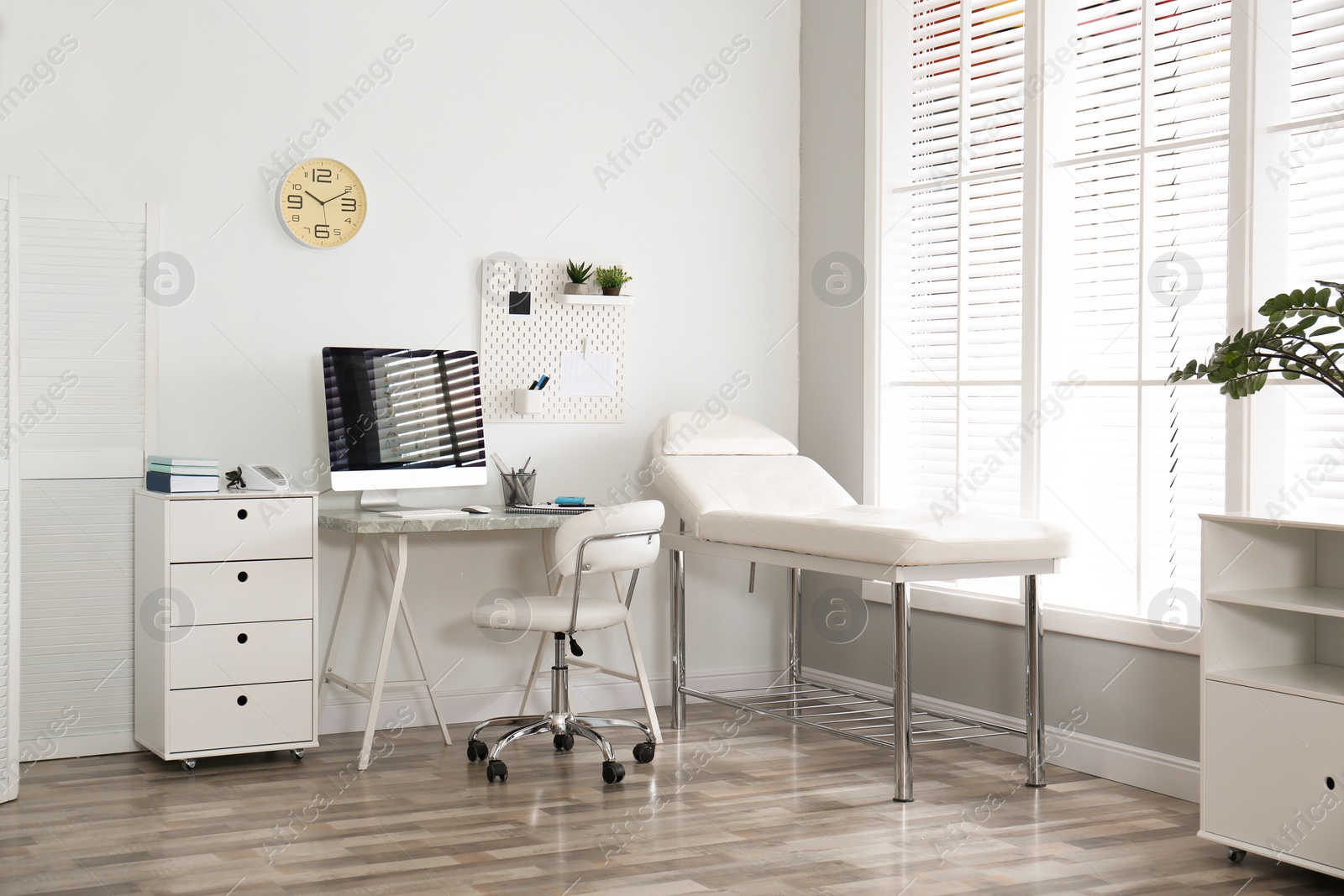 Photo of Modern medical office interior with computer and examination table