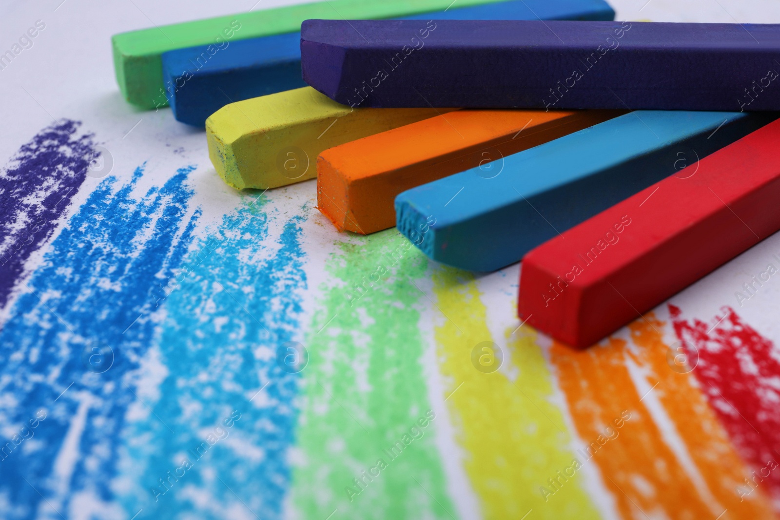 Photo of Colorful pastel chalks and scribbles on white background, closeup. Drawing materials