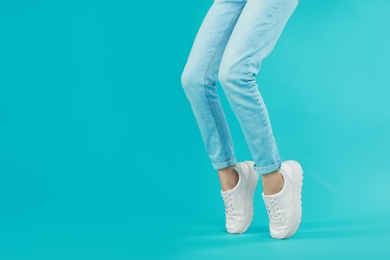 Photo of Woman in stylish sport shoes on light blue background. Space for text