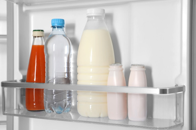 Different bottles in basket of modern refrigerator