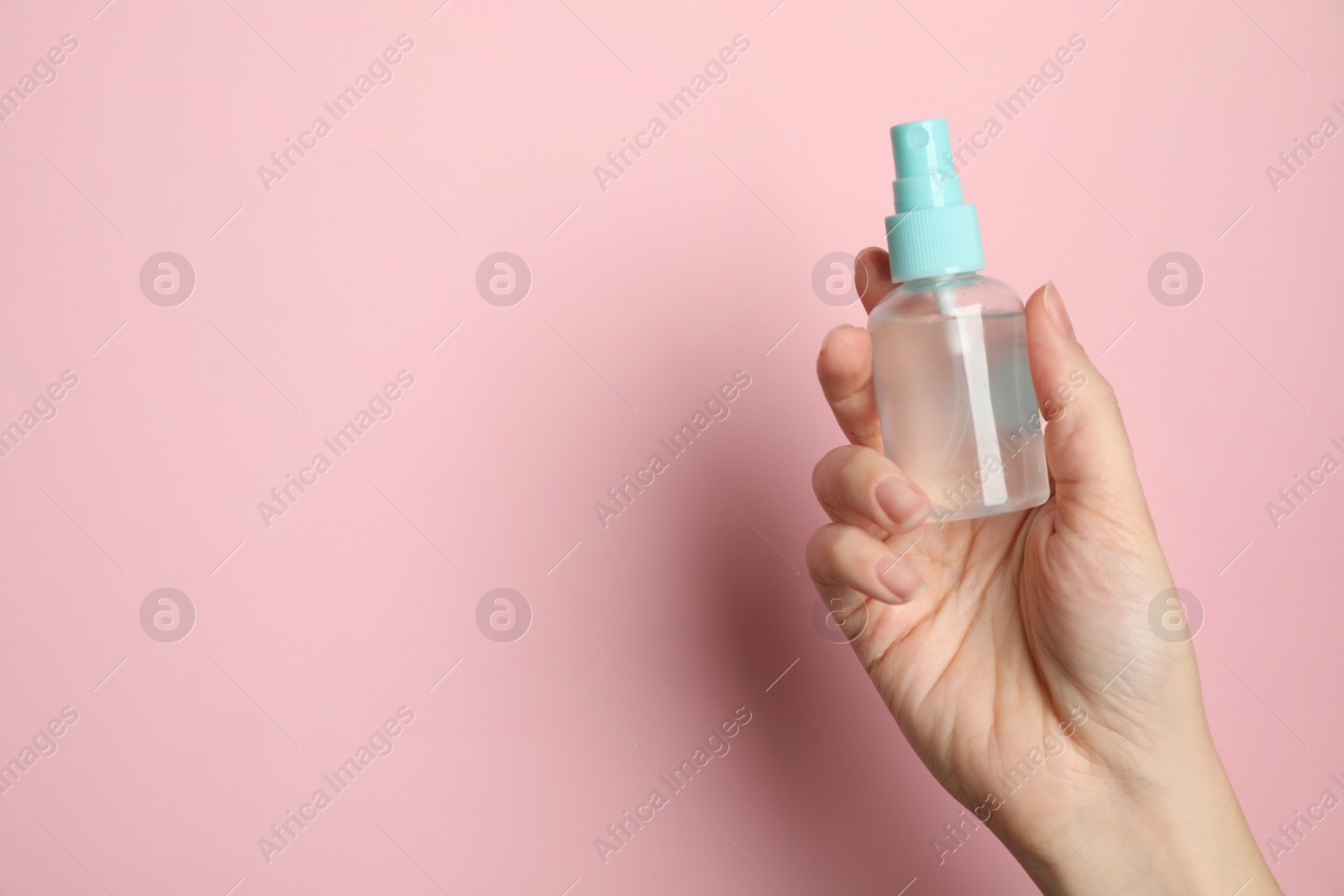 Photo of Woman holding antiseptic spray on pink background, closeup. Space for text