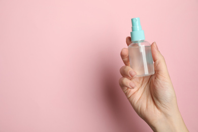Photo of Woman holding antiseptic spray on pink background, closeup. Space for text