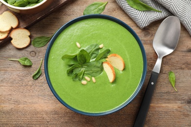 Flat lay composition with fresh green healthy spinach soup on wooden table