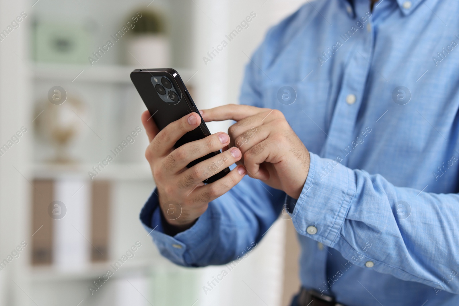 Photo of Man using smartphone in office, closeup view