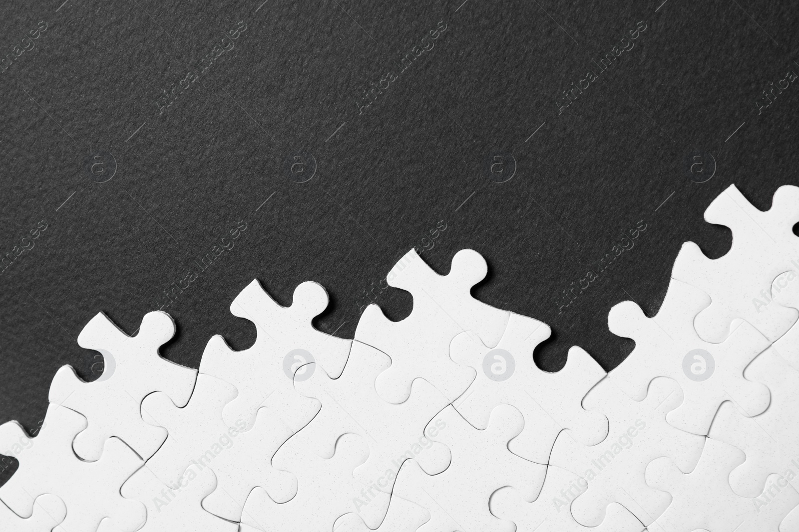 Photo of Blank white puzzle pieces on black background, flat lay. Space for text