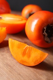 Photo of Delicious ripe persimmons on wooden table, closeup