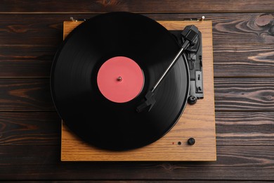 Photo of Modern vinyl record player with disc on wooden background, top view