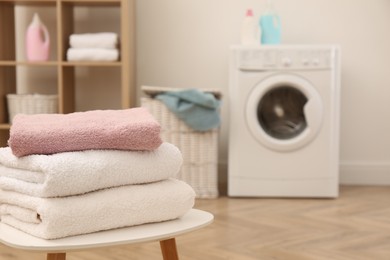 Photo of Stack of clean terry towels on white table in laundry room. Space for text