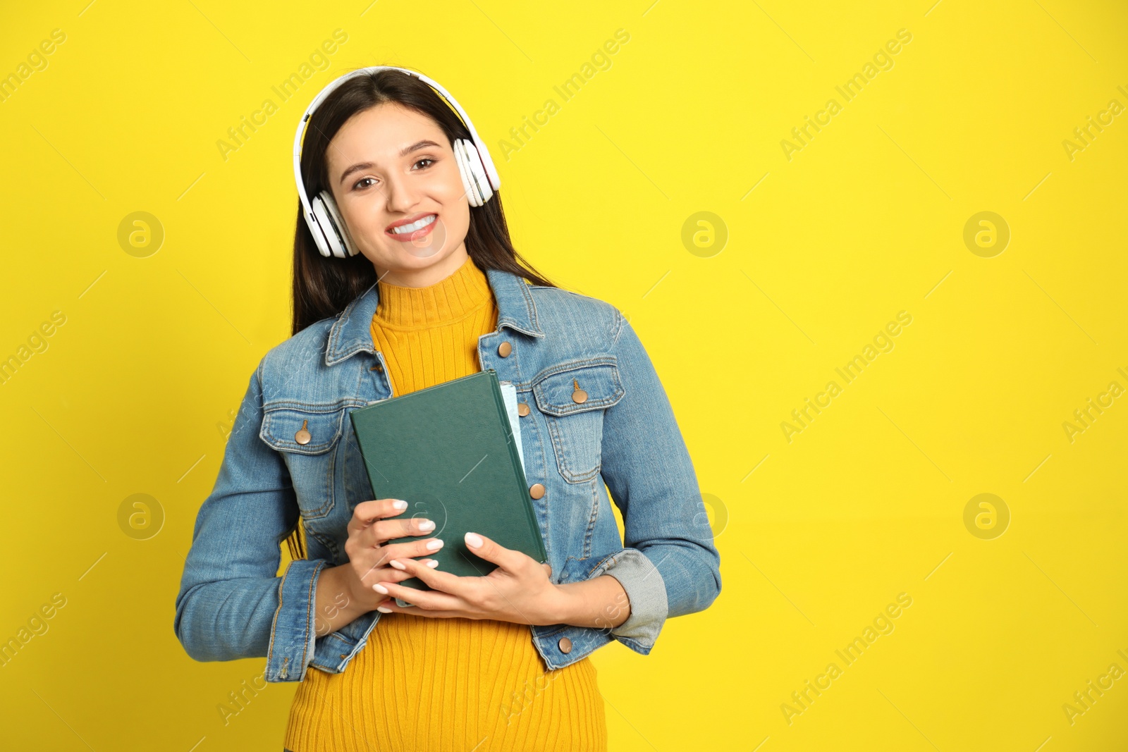 Photo of Young woman listening to audiobook on yellow background. Space for text