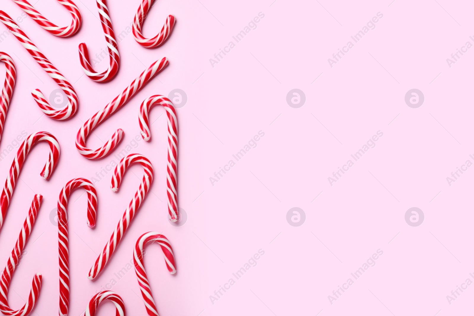 Photo of Sweet Christmas candy canes on pink background, flat lay. Space for text
