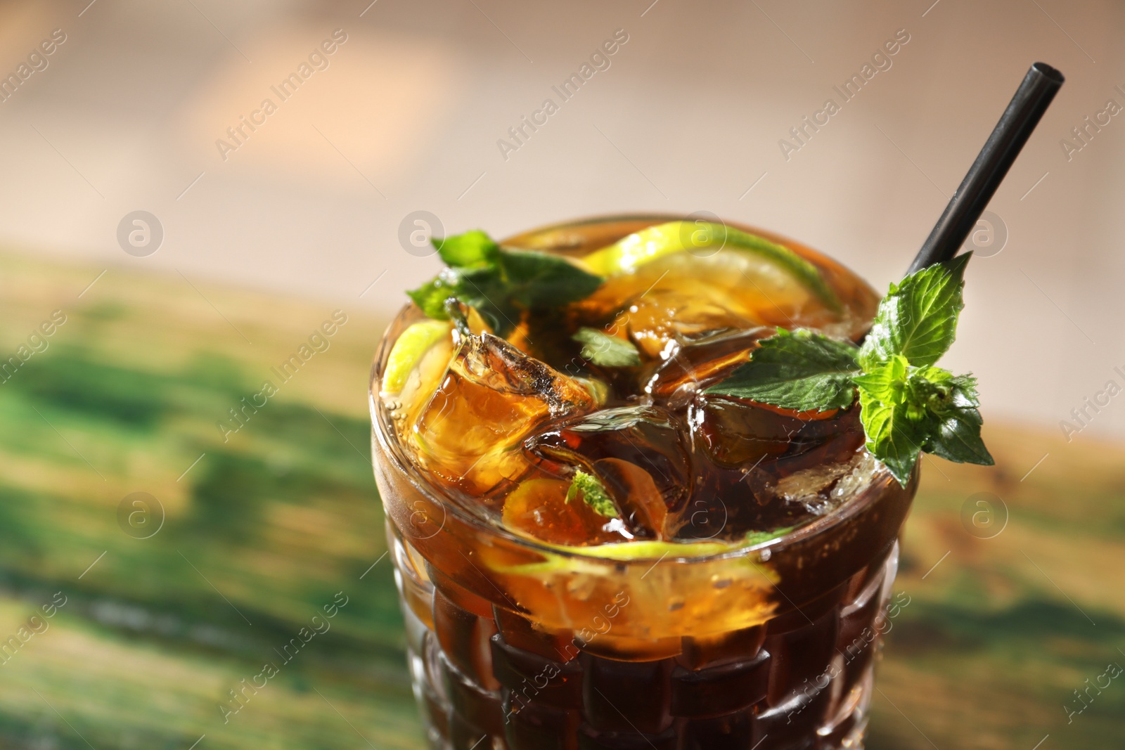 Photo of Glass of delicious cocktail with ice on table, closeup