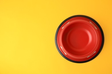 Empty red feeding bowl on orange background, top view. Space for text