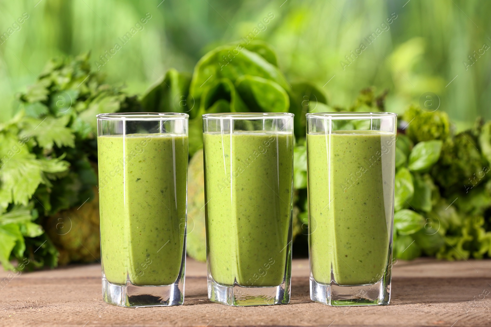 Photo of Glasses of fresh green smoothie and ingredients on wooden table