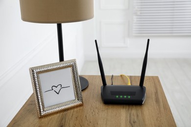 Modern Wi-Fi router on wooden table in room