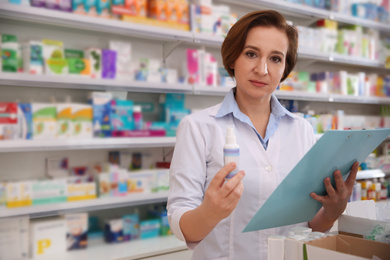 Image of Professional pharmacist with clipboard and medicine in drugstore