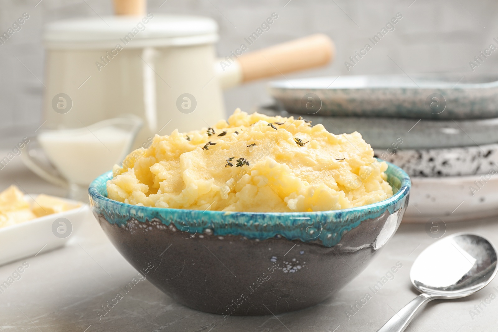 Photo of Bowl with tasty mashed potato on gray table