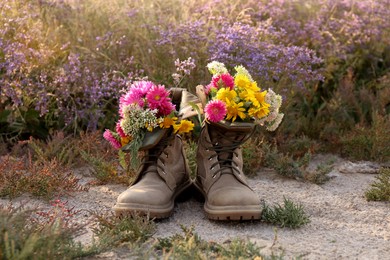 Boots with beautiful wild flowers in meadow