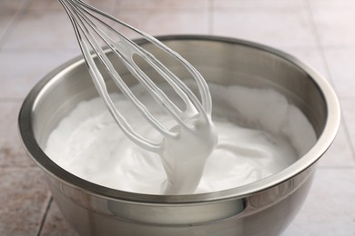 Photo of Bowl and whisk with whipped cream on tiled table