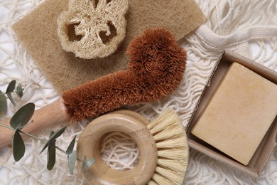 Photo of Cleaning brushes, sponge, loofah, soap bar and eucalyptus leaves on table, top view