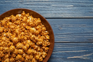 Photo of Delicious popcorn with caramel on wooden background, top view