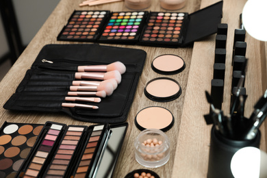 Photo of Set of different professional makeup products on wooden table in studio