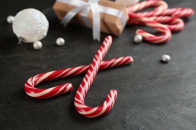 Photo of Sweet candy canes and Christmas decor on black table