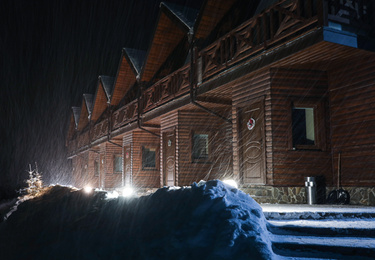 Photo of Wooden hotel on snowy evening. Winter vacation